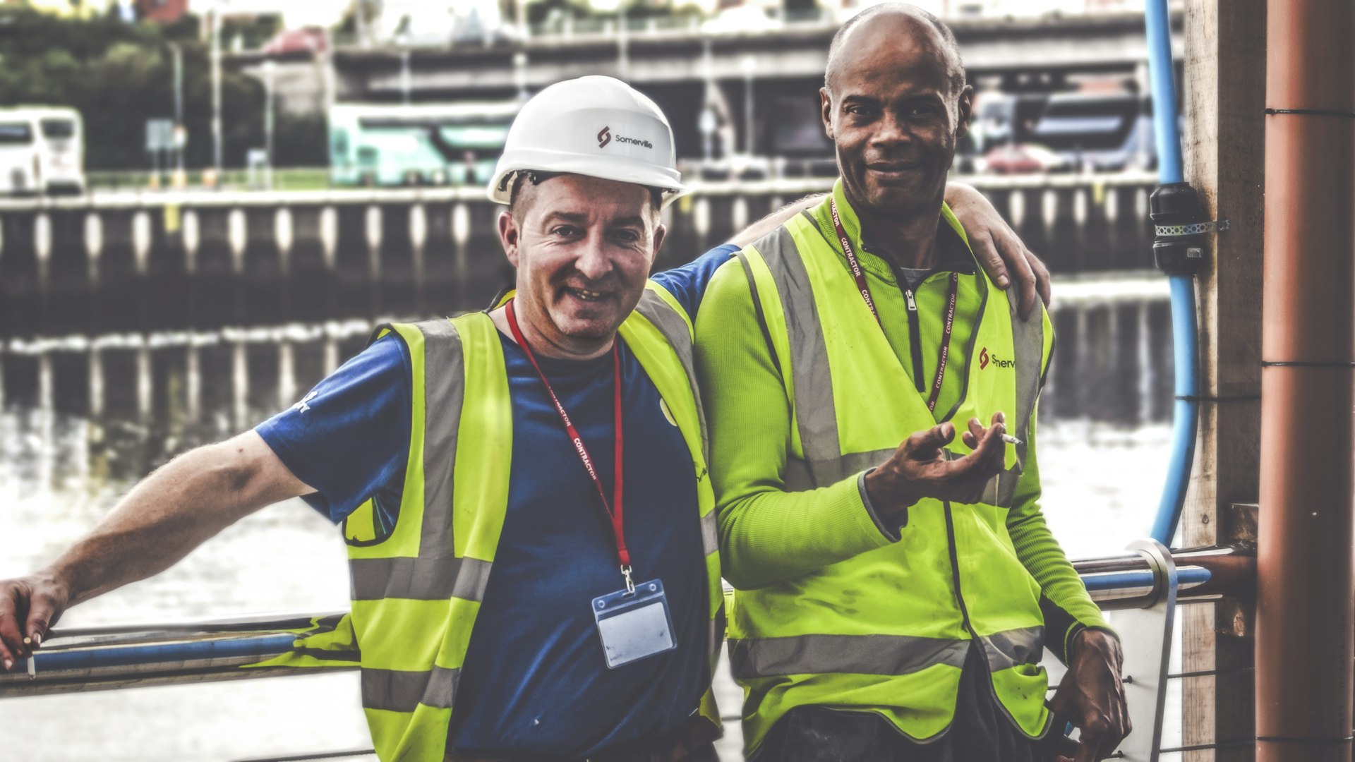 two construction workers standing next to each other smiling for the camera